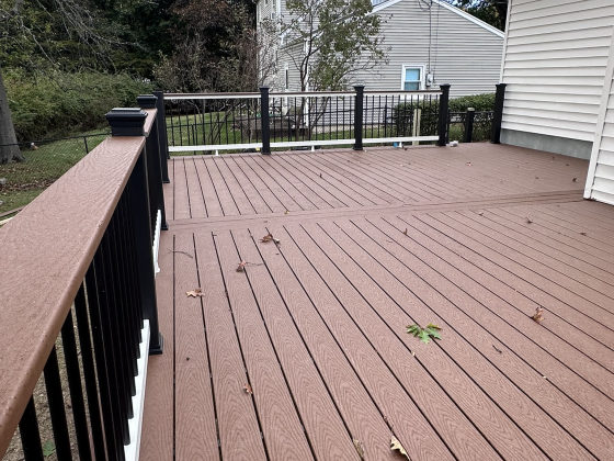 New composite deck with black metal railing overlooking residential yard